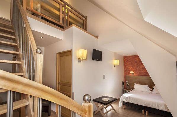A bedroom with a wooden staircase, a bed, a nightstand, and a TV. - Logis Hôtel Restaurant Les 2 Rives - A75, en bordure de rivière (Banassac)