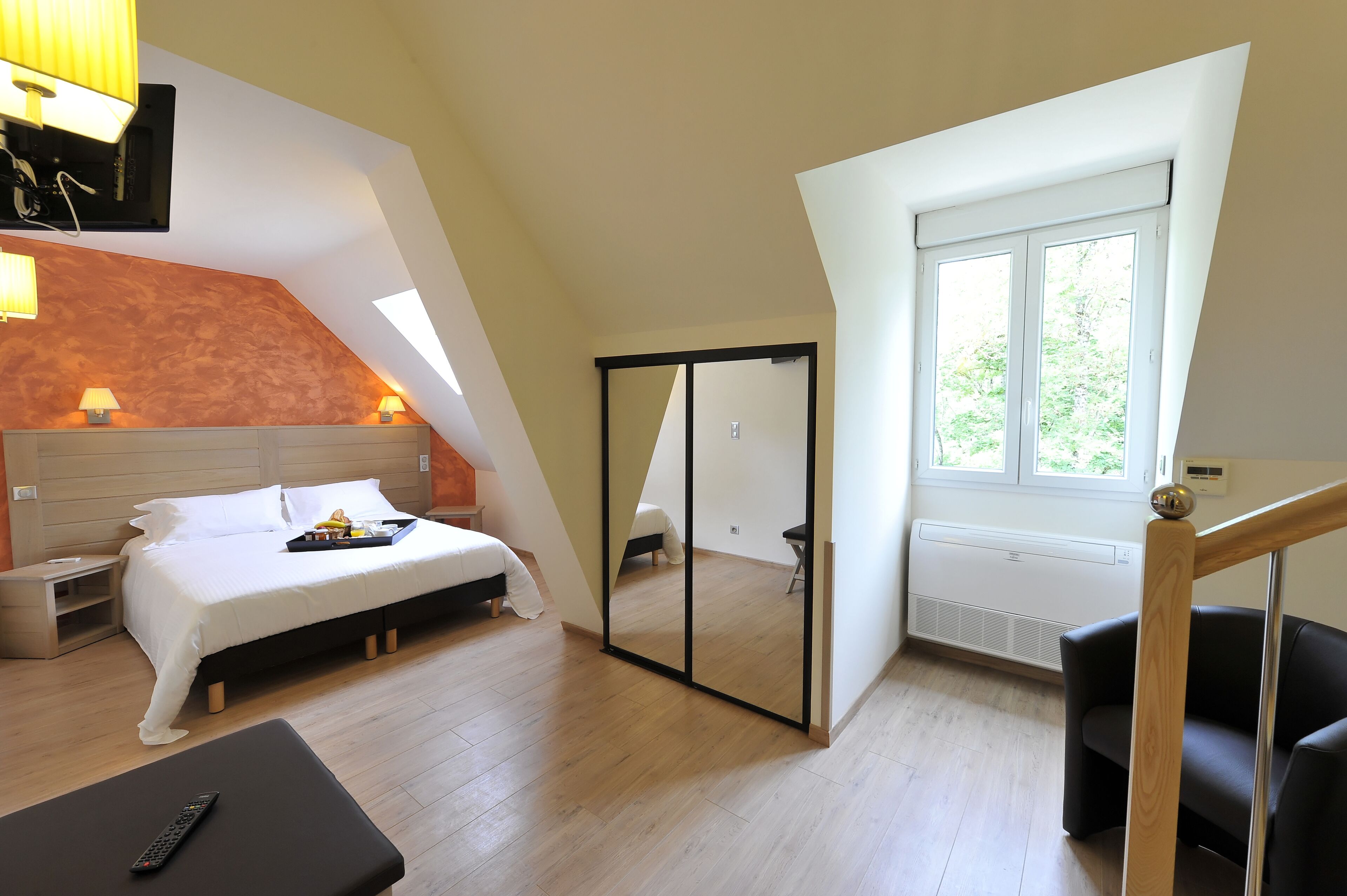 Une chambre à coucher avec un lit, une table de chevet, une lampe et un miroir.