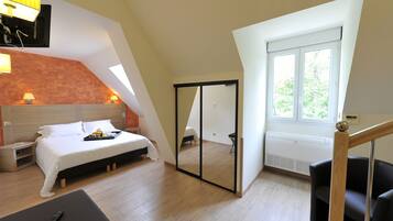 A bedroom with a bed, bedside table, lamp, and a mirror.