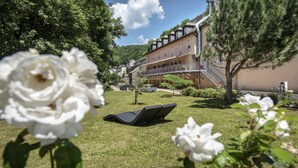 Hotel amb zona de jardí, incloent una cadira de relax i flors blanques.