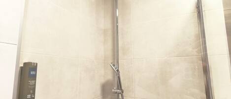 A shower with a handheld showerhead and a wall-mounted control panel.