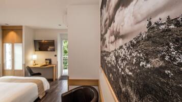 Une chambre d’hôtel avec un lit, un bureau, une chaise et un grand tableau au mur.