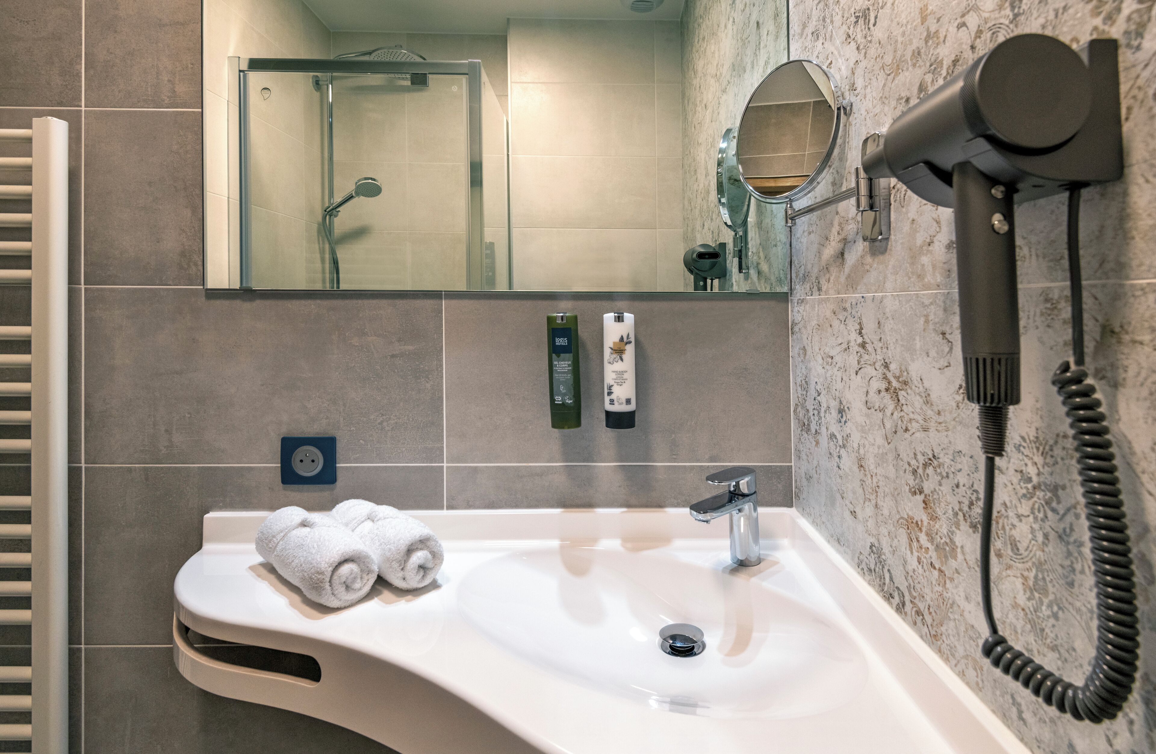A bathroom with a sink, towel, mirror, and a hairdryer.