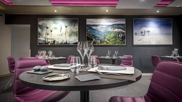 A conference room with round tables, purple chairs, and artwork on the walls.