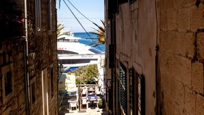 Una calle estrecha con un barco amarrado al final, un restaurante con mesas al aire libre y un edificio con un letrero que dice 