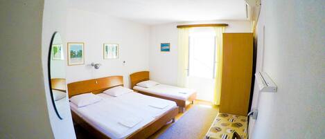 A hotel room with two beds, a small table, and a chair.