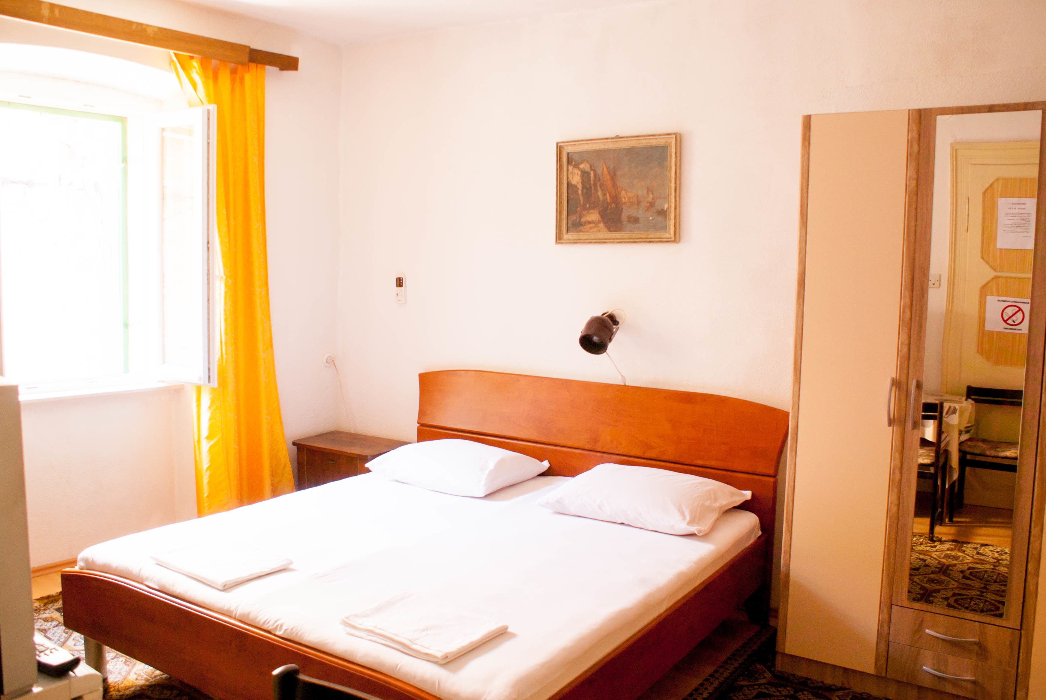 Een hotelkamer met een bed, nachtkastje, schilderij aan de muur en een kledingkast.