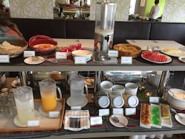 Un bufé con diversas opciones de comida y bebida, incluyendo leche fresca, fruta y yogur.