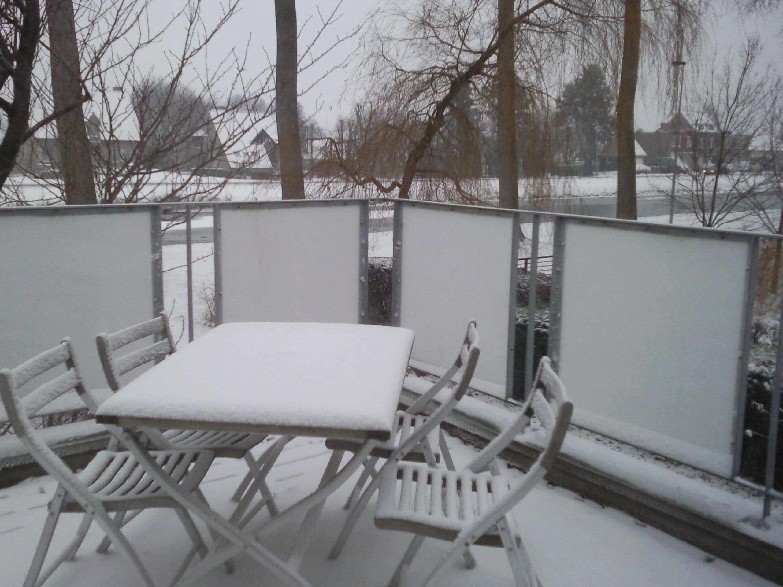 A snow-covered outdoor seating area with a table and chairs.