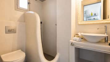 Un baño moderno con inodoro, ducha e lavamanos con espejo.