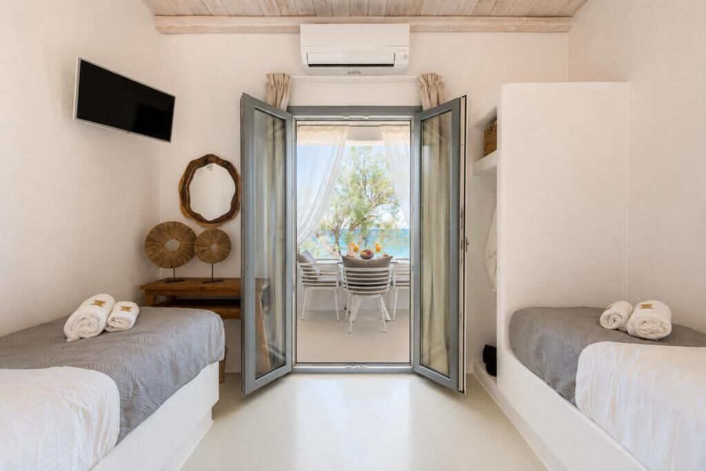 Un dormitorio con dos camas, televisor, aire acondicionado y vistas al exterior.