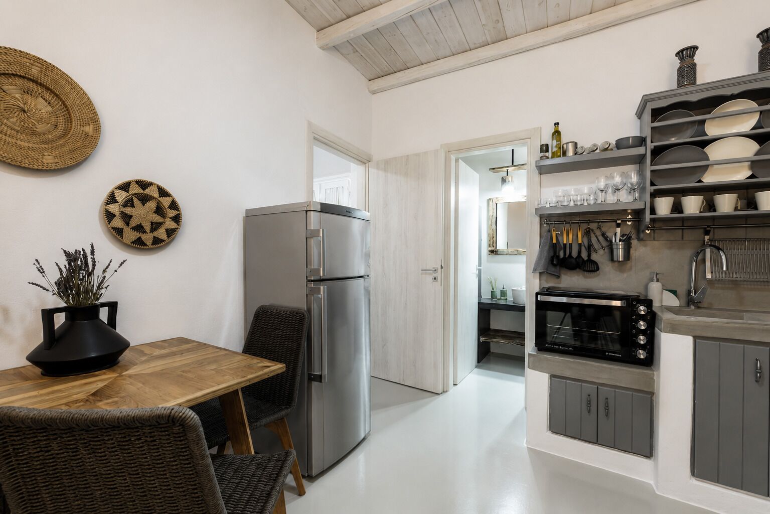 A modern kitchen with a refrigerator, microwave, and shelves with dishes.