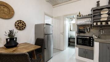 A modern kitchen with a refrigerator, microwave, and shelves with dishes.