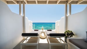 A balcony with a view of the ocean, two chairs, a small table with a vase, and a potted plant. - Blue Waves Suites & Apartments To Kyma (Paros)