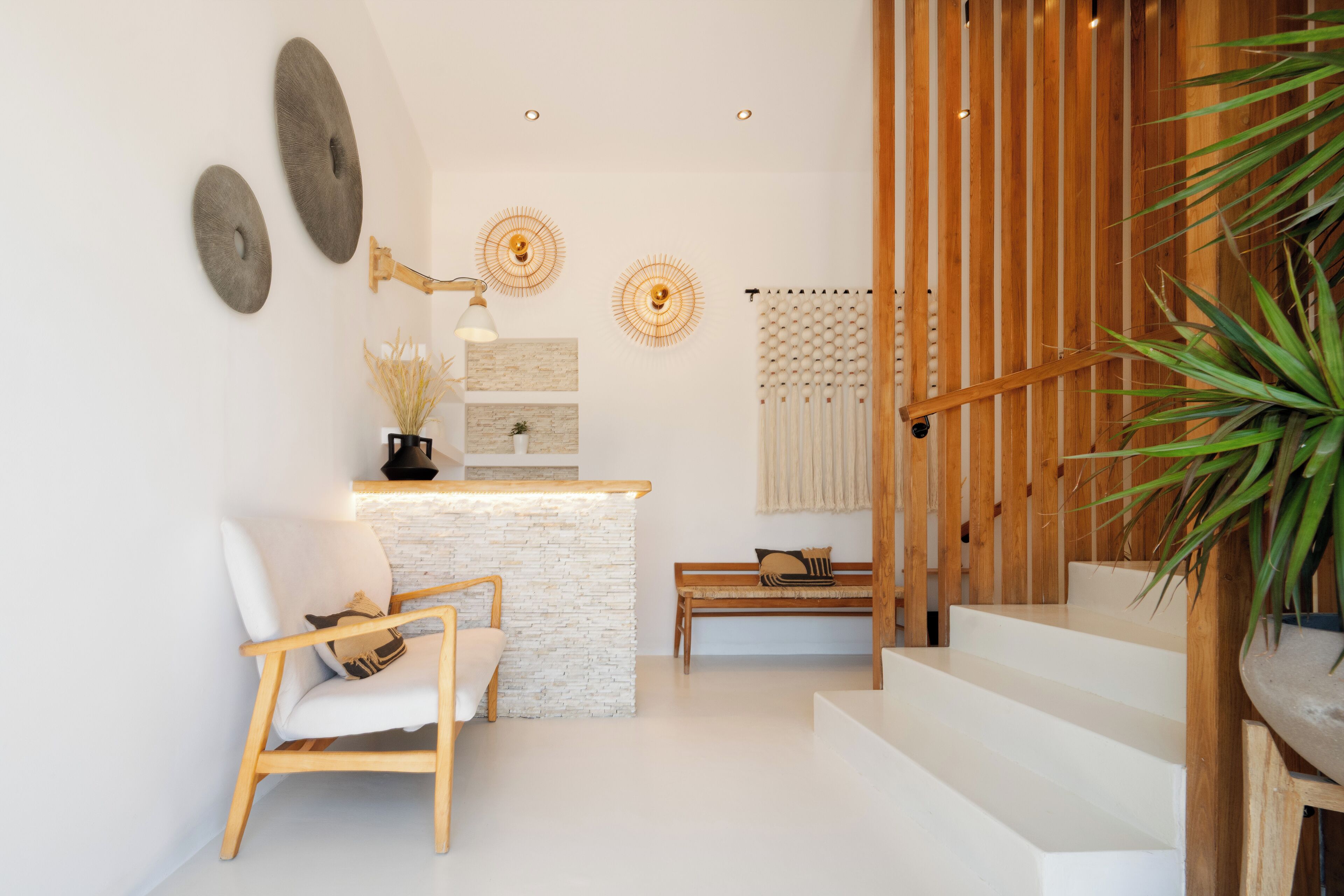 Un intérieur moderne avec un comptoir en pierre blanche, une chaise en bois et un escalier.