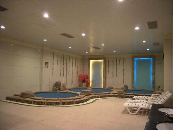 A spa area with multiple hot tubs, lounge chairs, and a reception desk. - Fengyuyan Hotel (Guilin)