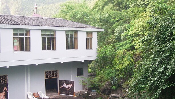 A two-story building with a swimming pool, surrounded by lush greenery and mountains. - Fengyuyan Hotel (Guilin)