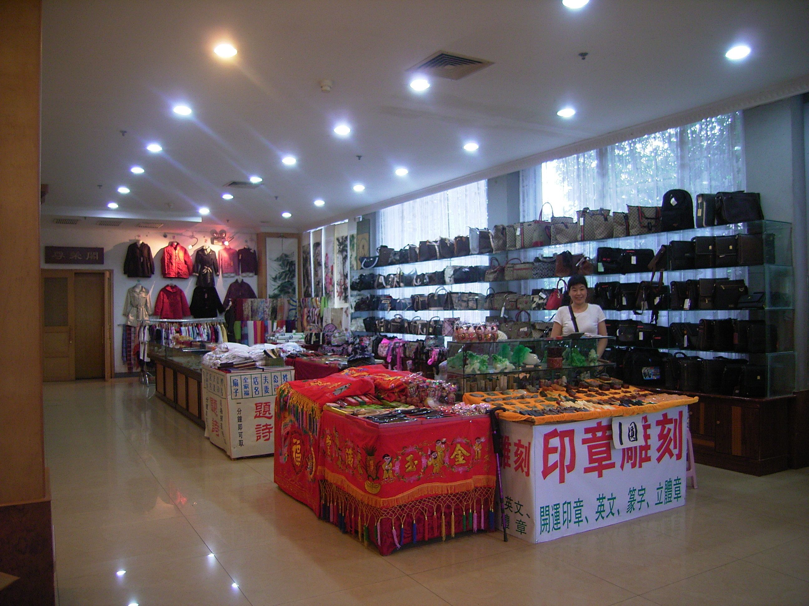 A well-lit store with shelves of handbags and a table displaying various items.
