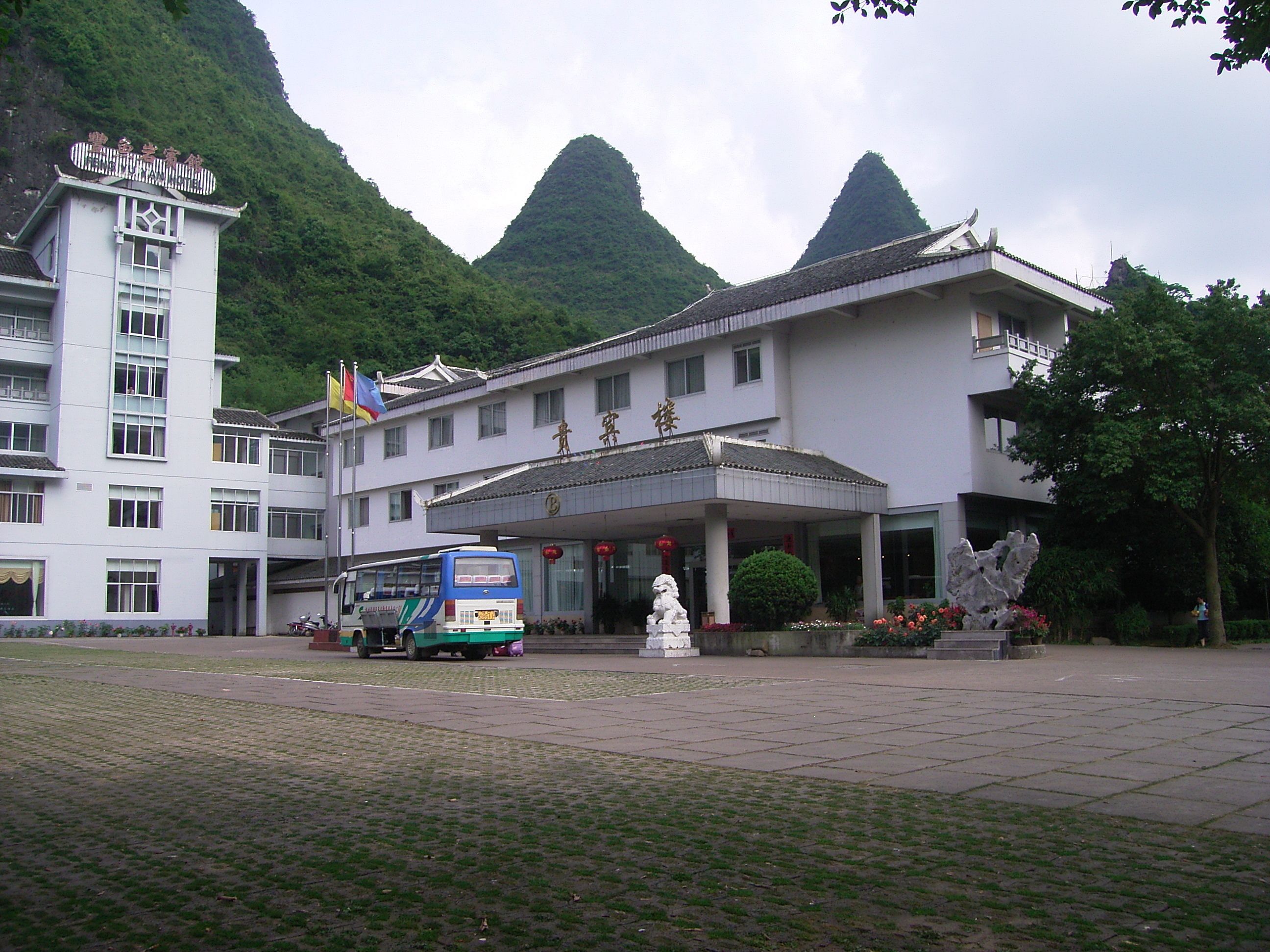 A hotel with a traditional architectural style, a covered entrance, and a statue in front.