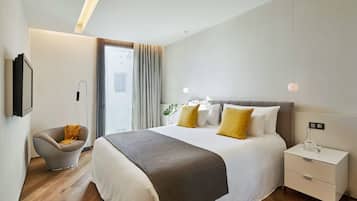 A modern hotel room with a large bed, a bedside table with a lamp, a chair, and a view of the city through the window.