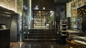 A modern lobby with a glass wall, a reception desk, and a staircase leading to an upper floor. - Ohla Barcelona (Barcelona)