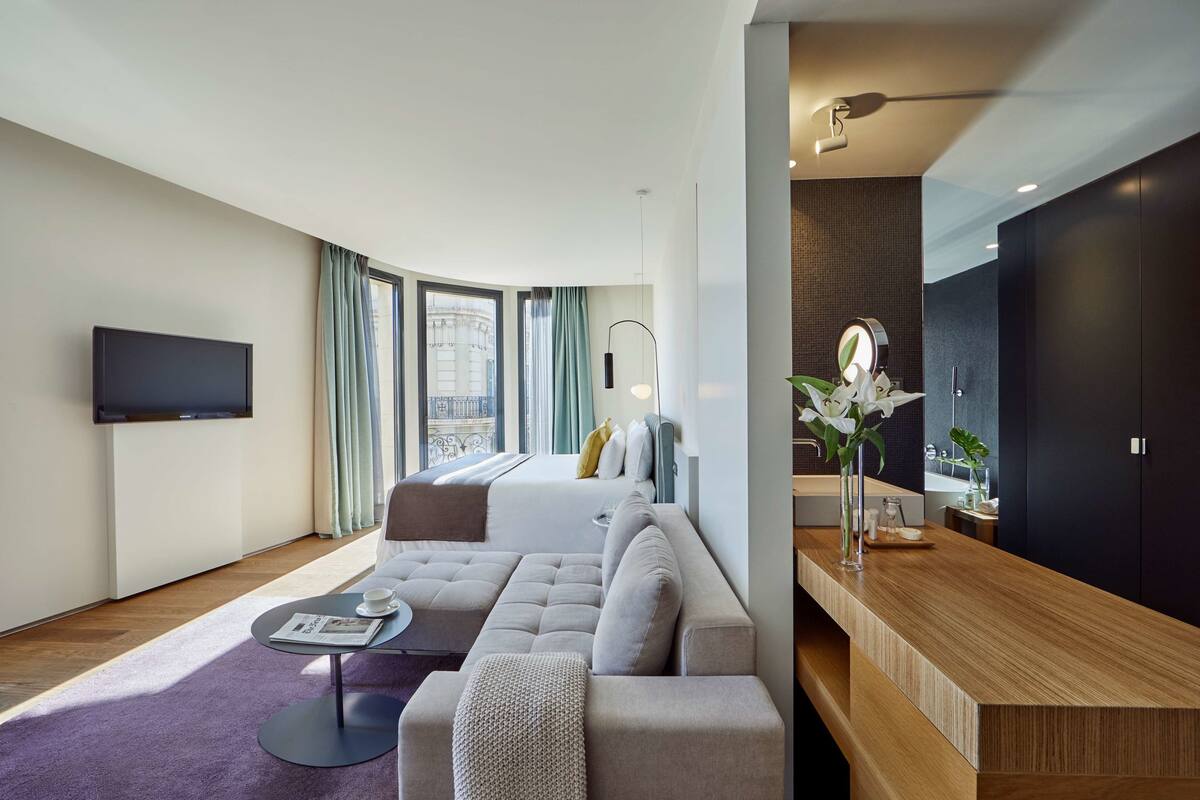A modern living room with a sectional sofa, a coffee table, and a TV mounted on the wall.