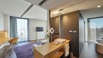 A modern hotel room with a wooden vanity, a large mirror, a bathtub, and a city view.