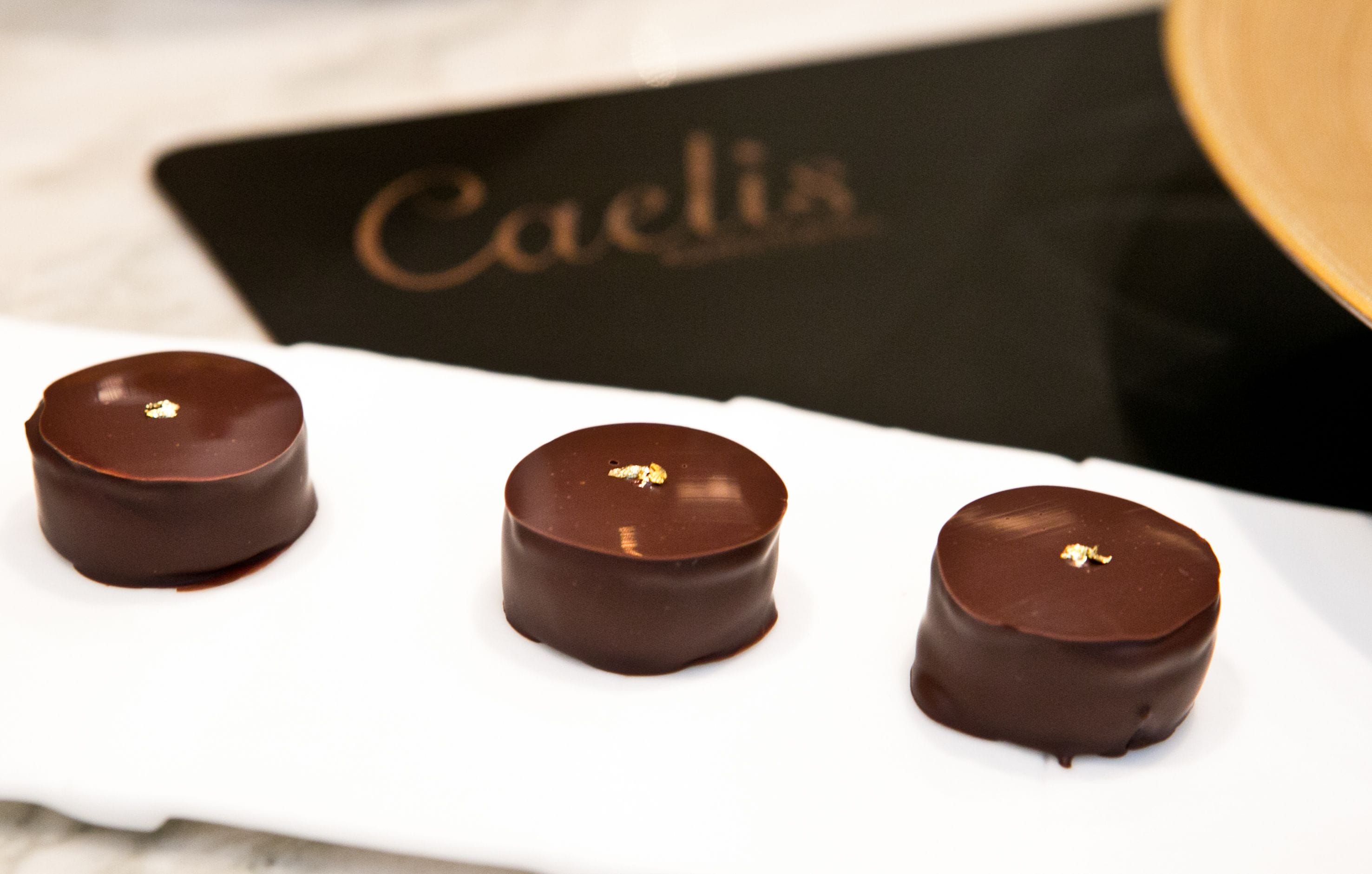 Three chocolate-covered confections on a white plate.