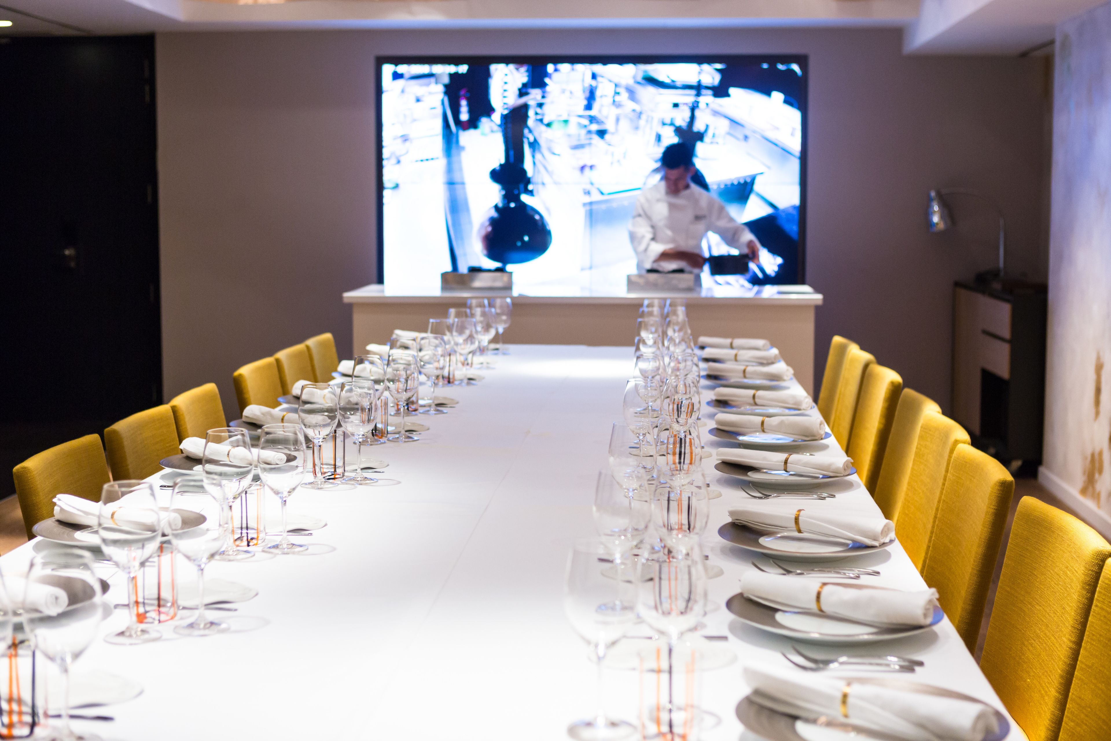 A long dining table set for a formal event with multiple chairs, glasses, and plates.