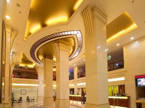 A spacious lobby with high ceilings, large columns, and a central circular light fixture. - Aiqun Hotel Guangzhou (Guangzhou)