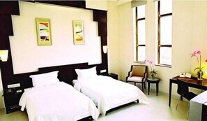 A hotel room with two beds, a desk, a chair, and two paintings on the wall. - Aiqun Hotel Guangzhou (Guangzhou)