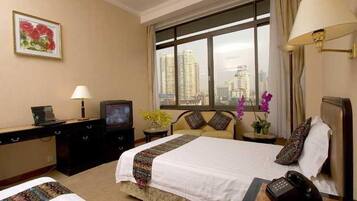 A hotel room with a bed, bedside table, lamp, TV, and a view of the city.