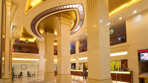 A spacious lobby with high ceilings, large columns, and a central circular light fixture. - Aiqun Hotel Guangzhou (Guangzhou)