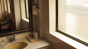 A bathroom with a sink, mirror, and window.