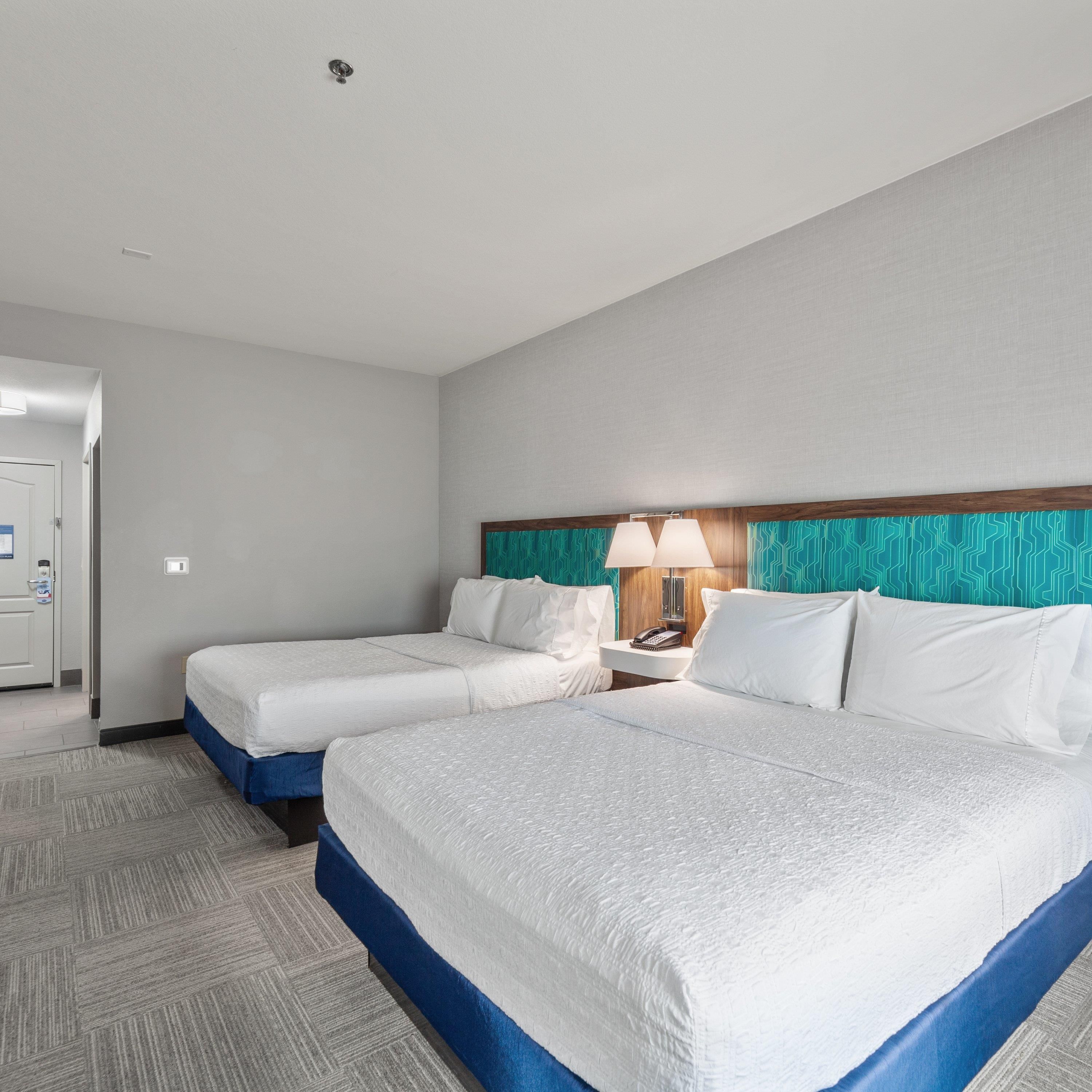Ein Hotelzimmer mit zwei Betten, einem Nachttisch mit Lampe und einer Tür mit Schloss.