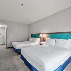 Una habitación de hotel con dos camas, una mesita de noche con una lámpara y una puerta con cerradura.