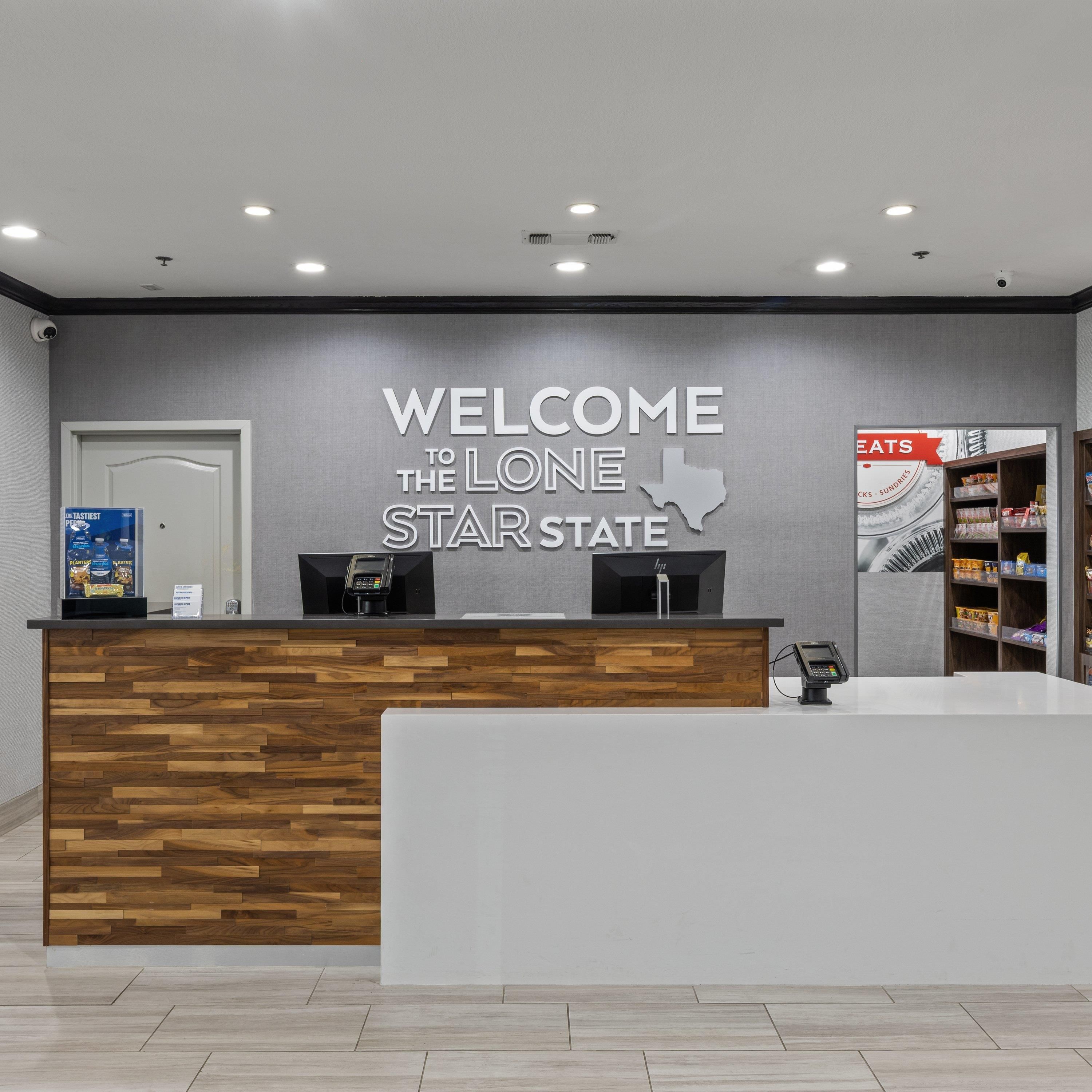 A reception desk with a welcome sign for Lone Star State, a phone, and a shelf with snacks.