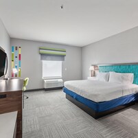 Una habitación de hotel con cama, mesita de noche, lámpara y escritorio con silla.