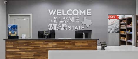 A reception desk with a welcome sign for Lone Star State, a phone, and a shelf with snacks.