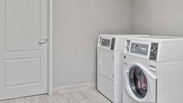A laundry room with two front-loading washing machines, a door, and a light switch on the wall.