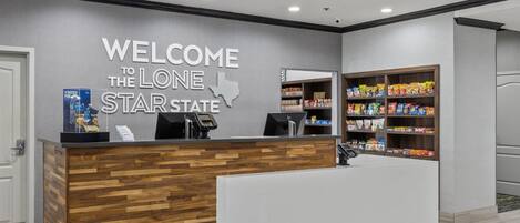 A reception desk with a welcome sign, a coffee machine, and a snack shelf.