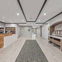 Un vestíbulo de hotel con mostrador de recepción, estación de café y vistas al área exterior.