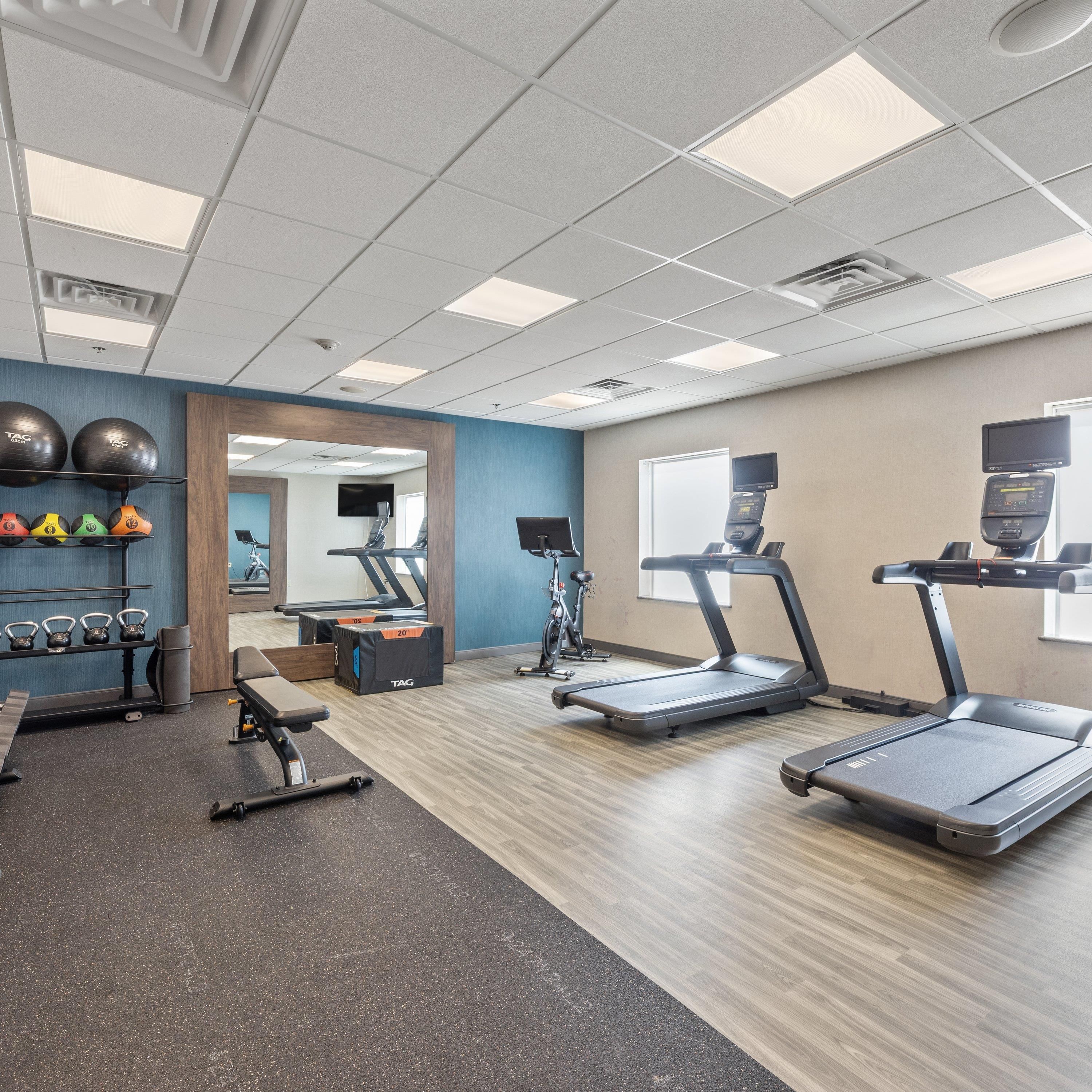 A gym with treadmills, a weight bench, kettlebells, and exercise balls.