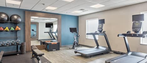 A gym with treadmills, a weight bench, kettlebells, and exercise balls.