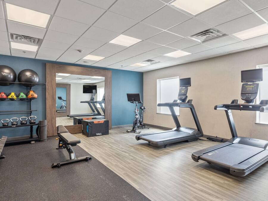 A gym with treadmills, a weight bench, kettlebells, and exercise balls.