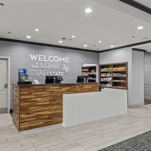 A reception desk with a welcome sign, a coffee machine, and a snack shelf.