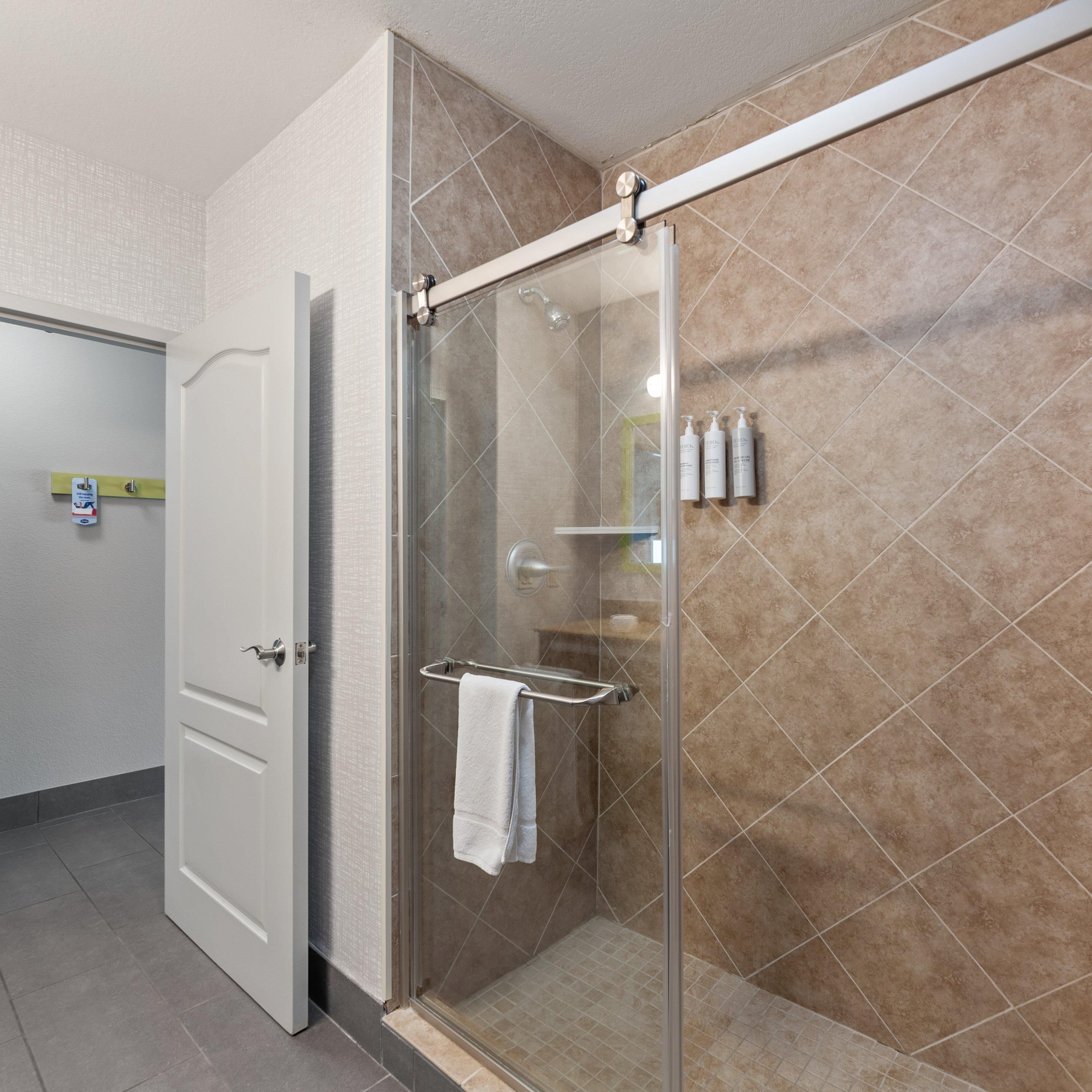 Un baño moderno con cabina de ducha de vidrio, toallero y artículos de aseo en la pared.