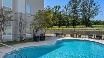 A swimming pool with a 3 FT depth marker, surrounded by a patio area with outdoor furniture.