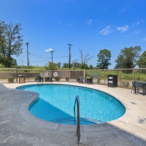 A swimming pool with a metal ladder, surrounded by a fence, and outdoor furniture. - Hampton Inn & Suites Denison (Denison)
