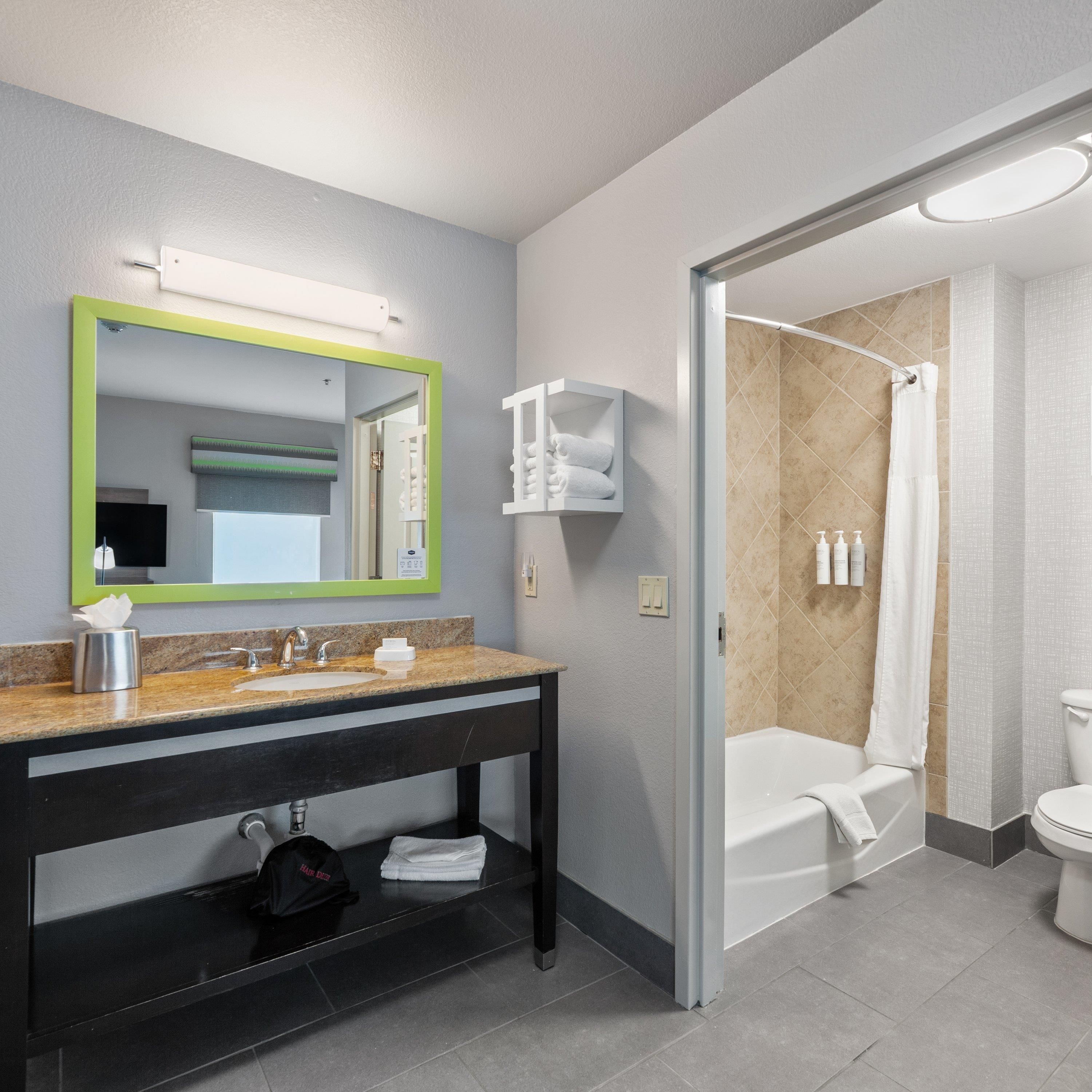 A modern bathroom with a sink, mirror, and shower area.